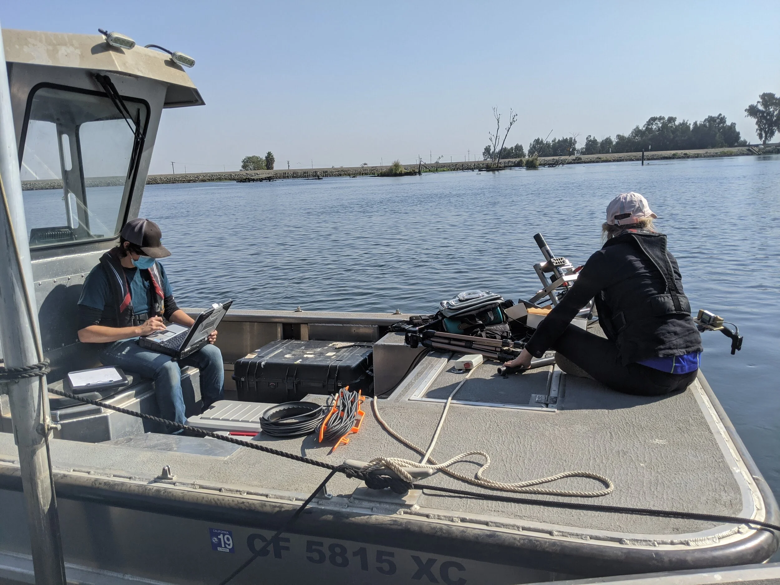 Two researchers with field equipment on a boat in the Sacramento-San Joaquin Delta