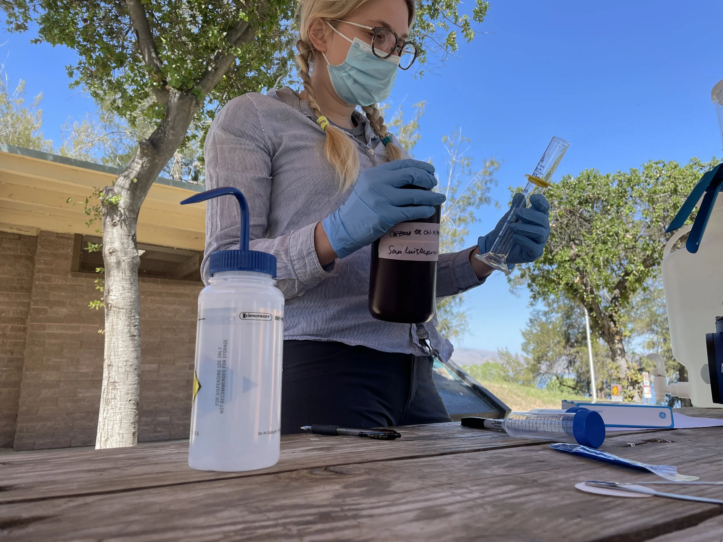 Water sample bottle labeled San Luis Reservoir with syringe filtration setup